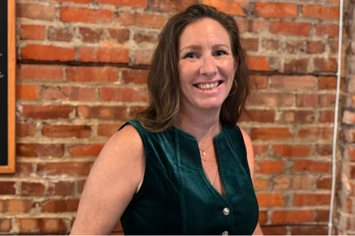Amber Hamilton, CEO of Redwood Rise, smiles in front of a brick wall.